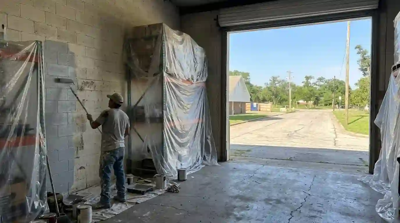 Painter rolling paint on a warehouse block wall in Haltom City