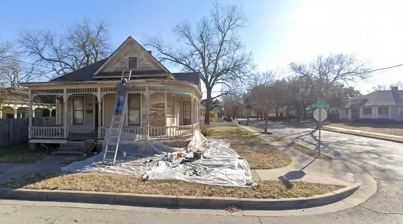 Painter hand scraping siding on a historic Fairmount Victorian cottage